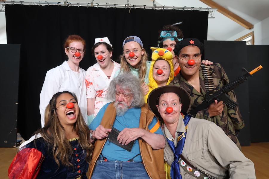 Clown instructor Philippe Gaulier surrounded by students in clown regalia.