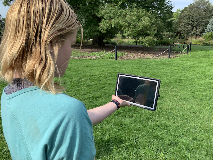 Girl holding a tablet, demonstrating the difficulty seeing the AR art in the sun.