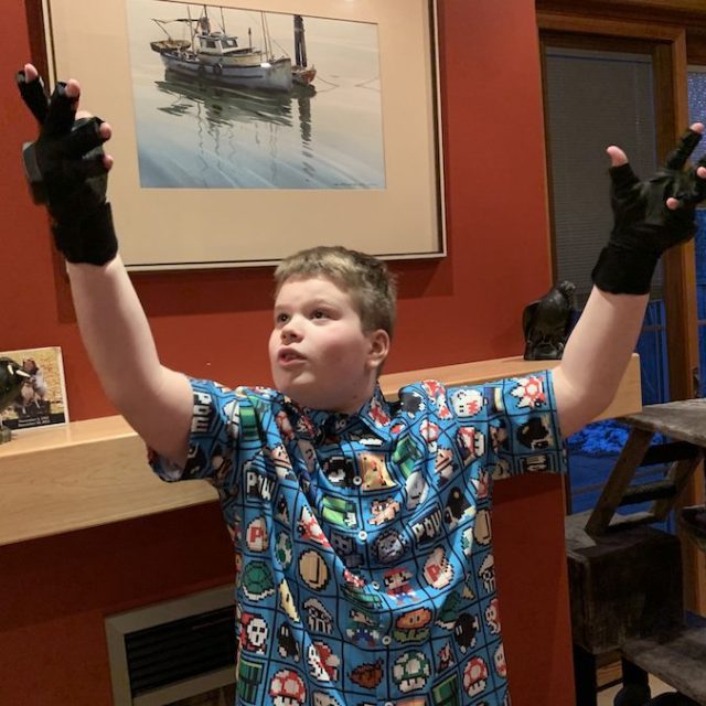 12-year-old boy, wearing an old school game shirt, playing with some Rokoko motion capture gloves.